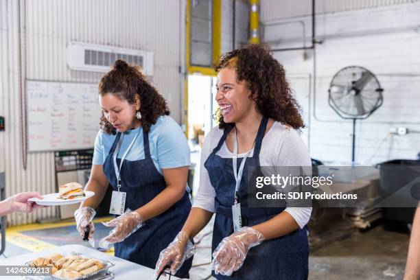 female volunteers serve sandwiches - soup kitchen stock pictures, royalty-free photos & images