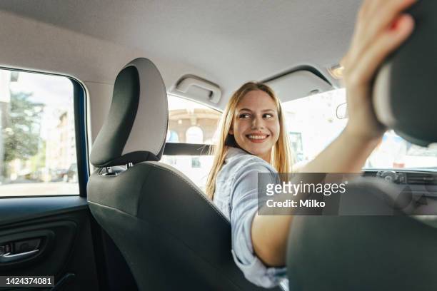 confident young woman driving car - reverse stockfoto's en -beelden