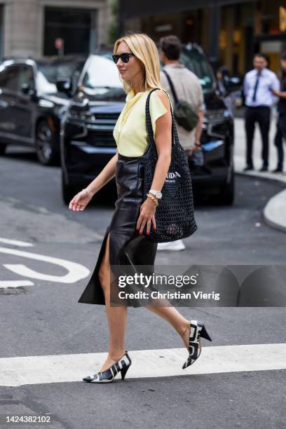 Lisa Aiken wearing Prada bag, black skirt with slit, yellow top, heels with black white print outside Peter on September 13, 2022 in New York City.