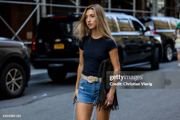 Guest wearing denim shorts, bag with fringes outside Cos on September 13, 2022 in New York City.