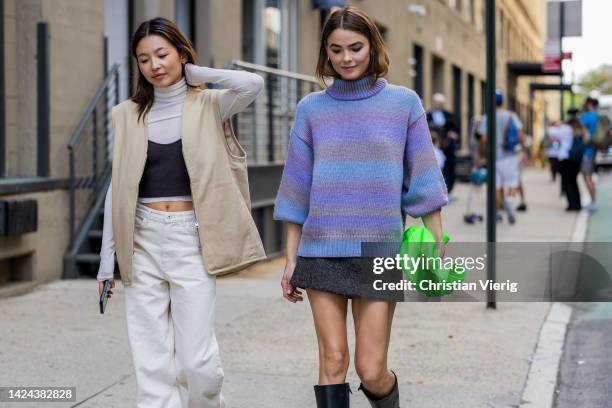 Yan Yan Chan wearing beige vest, white turtleneck and Bambi Northwood Blyth wearing turtleneck, green bag, skirt outside Cos on September 13, 2022 in...