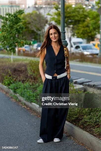 Gala Gonzalez wearing striped vest, wide leg pants, bag outside Tory Burch on September 13, 2022 in New York City.