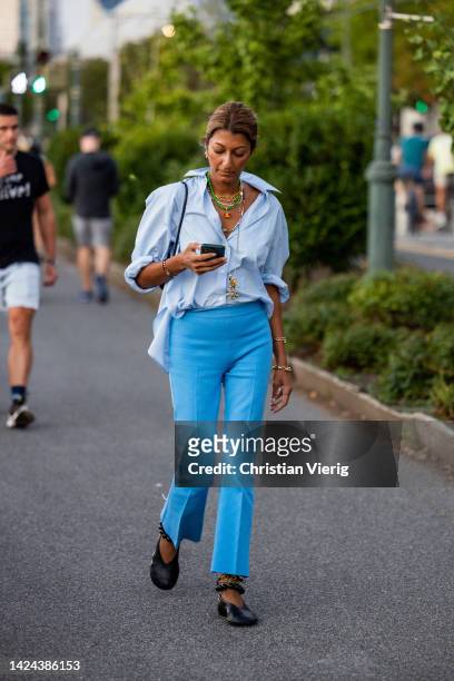 Guest wearing blue pants, button shirt, necklace outside Tory Burch on September 13, 2022 in New York City.