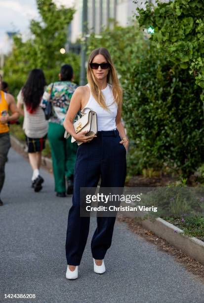 Charlotte Groeneveld wearing white bag, top, navy pants, heels outside Tory Burch on September 13, 2022 in New York City.