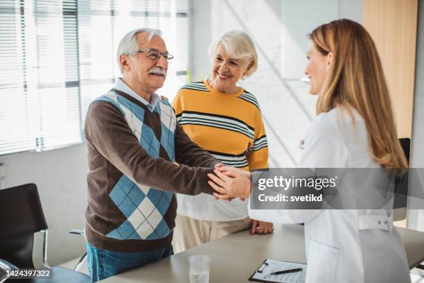 altes paar besuch den arzt - couple shaking hands with doctor stock-fotos und bilder