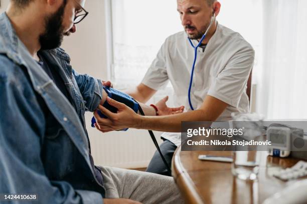 doctor on a house call measuring the blood pressure - altitude sickness stock pictures, royalty-free photos & images