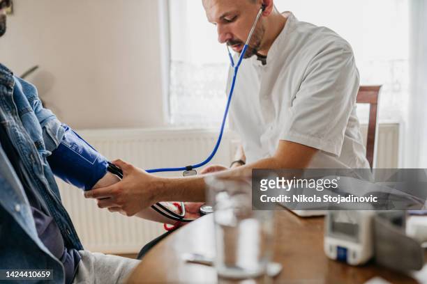 doctor on a house call measuring the blood pressure - altitude sickness stock pictures, royalty-free photos & images