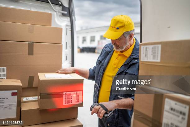 courier in uniform scanning order packages bar code in van trunk - old boots stock pictures, royalty-free photos & images