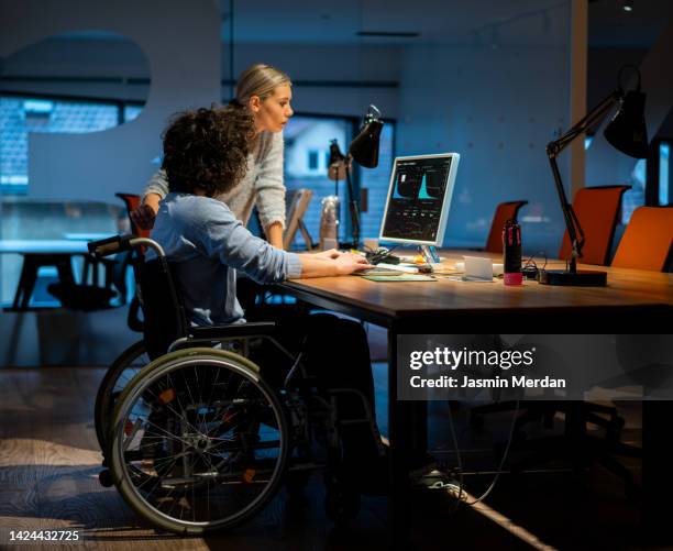 two young creative people discussing project at working place - diversidad cultural fotografías e imágenes de stock