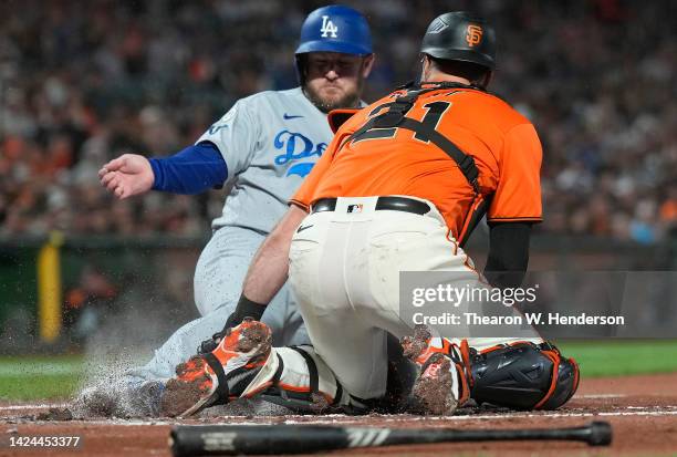 Max Muncy of the Los Angeles Dodgers sliding at home plate scores as the throw gets past Joey Bart of the San Francisco Giants in the top of the...