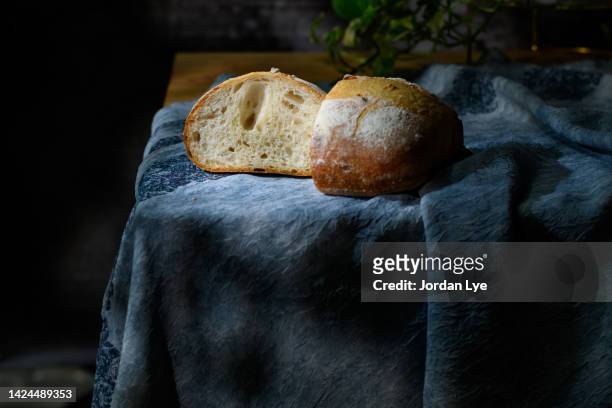 loaf of bread on wooden table on dark background in low key - close up bread roll black backdrop horizontal stock pictures, royalty-free photos & images