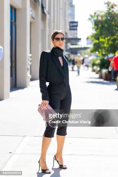 Thassia Naves wearing pink bag, black blazer, cropped pants, heels outside Michael Kors on September 14, 2022 in New York City.