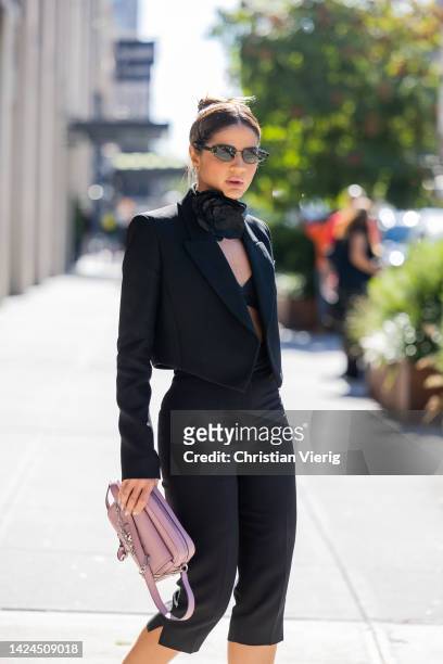 Thassia Naves wearing pink bag, black blazer, cropped pants, heels outside Michael Kors on September 14, 2022 in New York City.