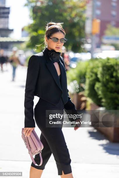 Thassia Naves wearing pink bag, black blazer, cropped pants, heels outside Michael Kors on September 14, 2022 in New York City.