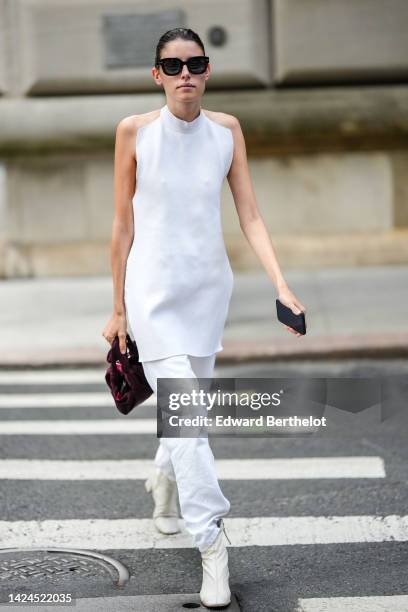 Guest wears black sunglasses, a white halter-neck / sleeveless / long silk blouse, white denim pants, a purple suede handbag, white latte leather...