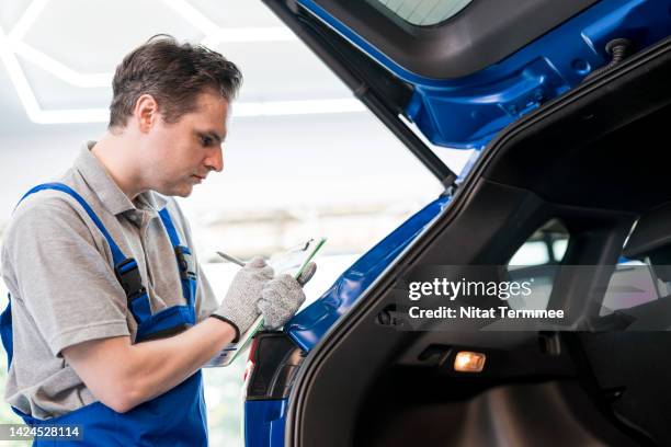 check before you drive your new car from the showroom. auto mechanics note on a pre-delivery inspection report and examine different parts of the exterior to spot any differences in the paint. - register bildbanksfoton och bilder