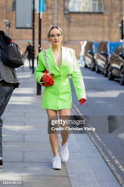 Guest wears neon cut out blazer, orange gloves outside Fashion East during London Fashion Week September 2022 on September 16, 2022 in London,...