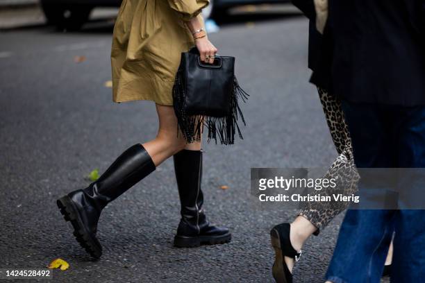 Guest wears bag with fringes, black boots outside Edward Crutchley during London Fashion Week September 2022 on September 16, 2022 in London, England.
