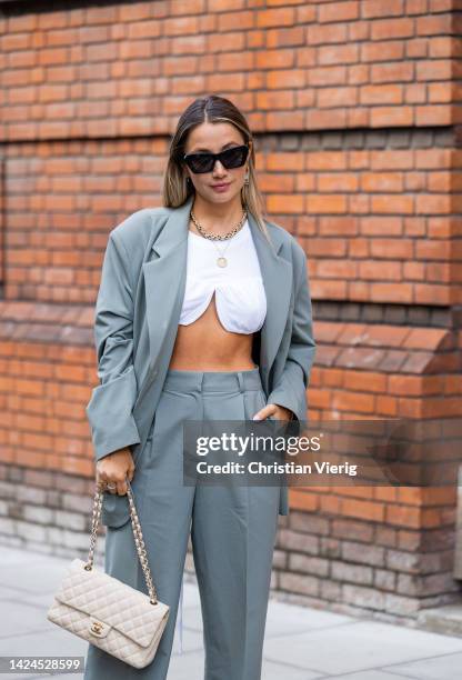 Guest wears a white cropped shirt, oversized blazer, Loewe sunglasses, pants outside Bora Aksu during London Fashion Week September 2022 on September...