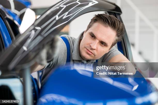 car door weather stripping and seal to reduce noise and water leaks. auto mechanics examine the rubber seal on a car door during servicing periods in an auto repair service center. - windshield replacement stock-fotos und bilder