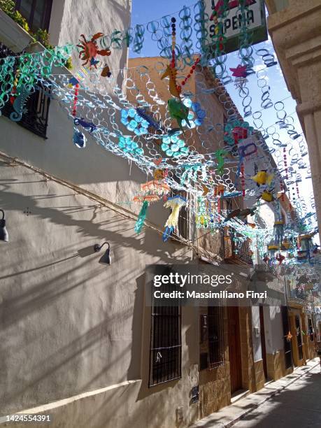 street suspended decoration in a narrow street in xàbia in spain - javea stock pictures, royalty-free photos & images