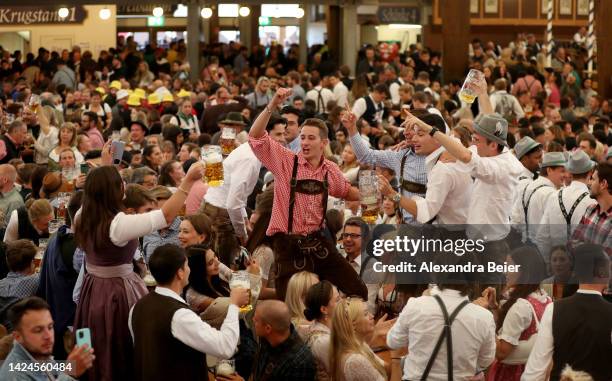 Revelers sing and hold up one liter glasses of beer in the Paulaner tent on the opening day of the 2022 Oktoberfest beer fest on September 17, 2022...