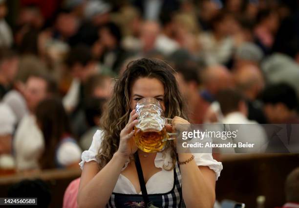 Woman drinks from a one liter glass of beer in the Paulaner tent on the opening day of the 2022 Oktoberfest beer fest on September 17, 2022 in...
