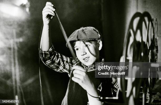 il proiezionista sorridente del film boy in vintage cap sta esaminando il cinema 16 mm - equipe cinematografica foto e immagini stock