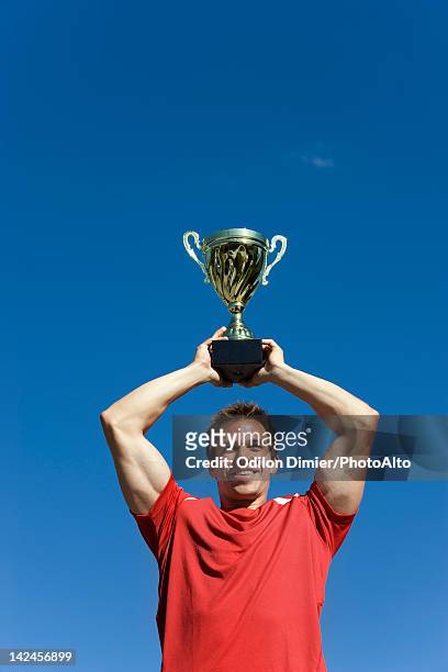 man holding up trophy cup - trophy day 1 photos et images de collection