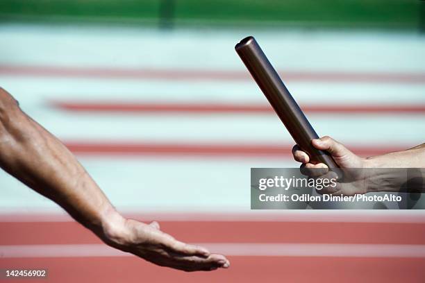 runners exchanging baton during relay race, cropped - relais athlétisme mains photos et images de collection