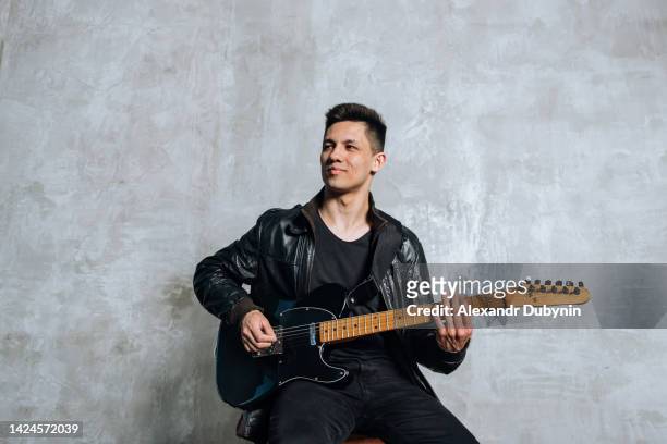 man rock guitarist plays the guitar while sitting - asian musician stock pictures, royalty-free photos & images