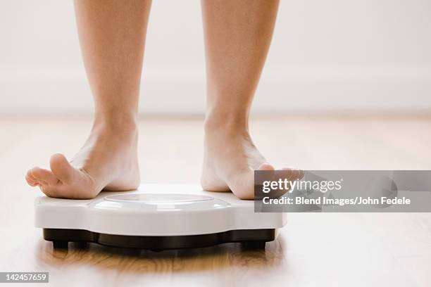 caucasian woman's feet standing on scale - weight loss stockfoto's en -beelden