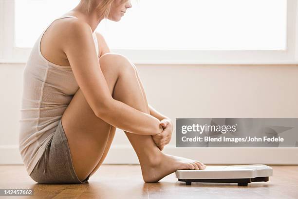 caucasian woman sitting on floor near scale - balansvåg bildbanksfoton och bilder