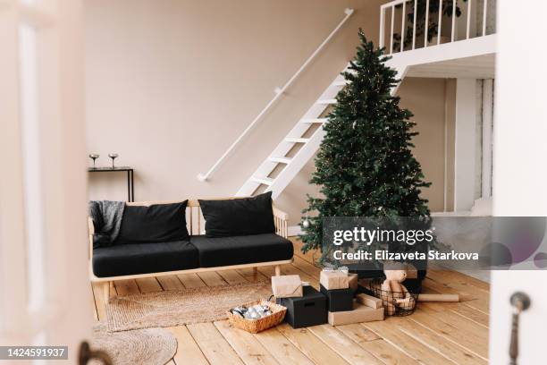 the concept of christmas interior design. a bright scandinavian-style interior with a hand made sofa decorated with a christmas tree and a wooden floor of the house.  festive new year's interior in eco friendly style in the apartment - christmas tree stockfoto's en -beelden