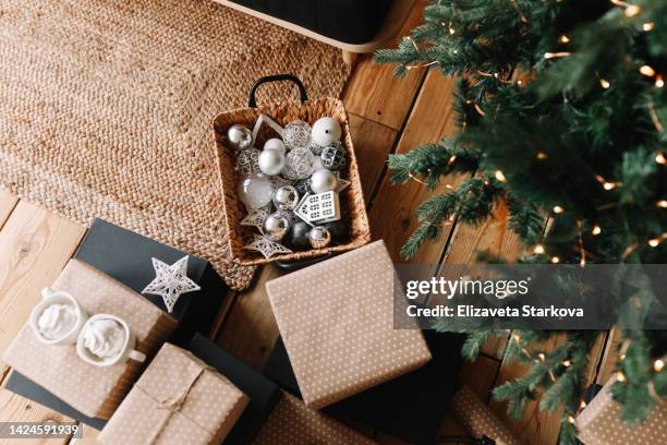 the concept of christmas photography. a new year's picture with festive gift boxes, christmas balls in a wicker basket and toys lying on the wooden floor in a cozy room at home in winter. top view - christmas tree stockfoto's en -beelden