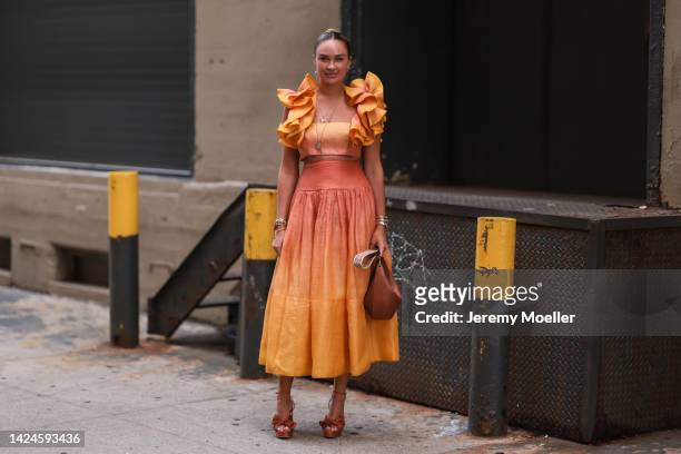 Nina Suess is seen wearing an orange ruffled long dress, brown leather Loewe bag and brown suede leather heels, outside COS, during New York Fashion...