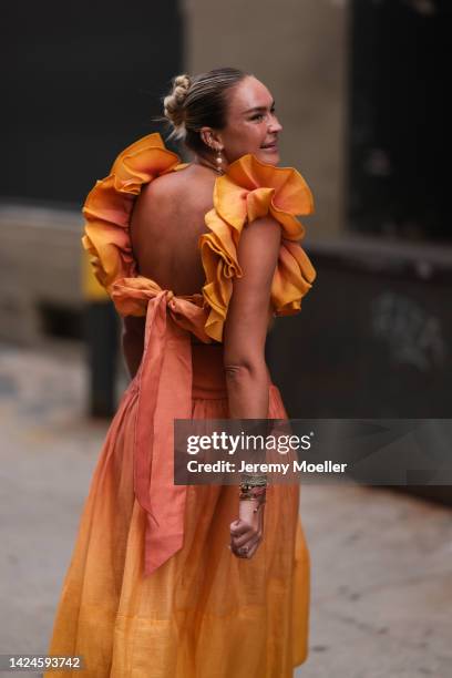 Nina Suess is seen wearing an orange ruffled long dress and a brown leather Loewe bag, outside COS, during New York Fashion Week on September 13,...