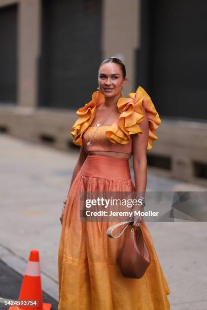 Nina Suess is seen wearing an orange ruffled long dress and a brown leather Loewe bag, outside COS, during New York Fashion Week on September 13,...