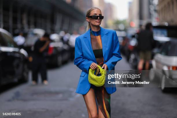 Leonie Hanne is seen wearing black Prada sunglasses, black transparent asymmetrical long dress with colorful pattern, blue oversize blazer, green...