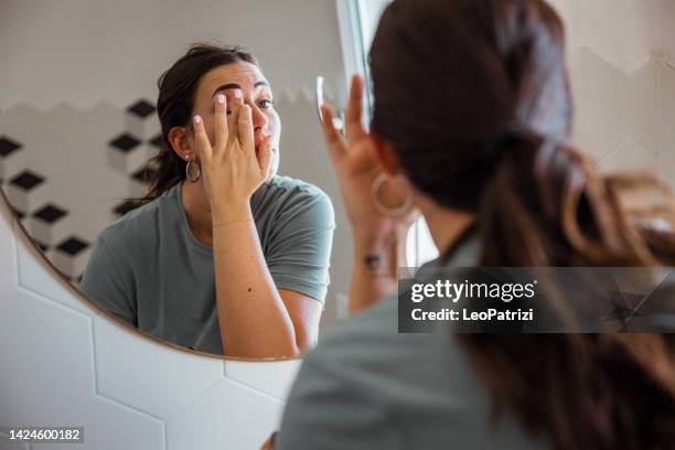 woman fixing make-up in front of the bathroom mirror - eye make up stock pictures, royalty-free photos & images