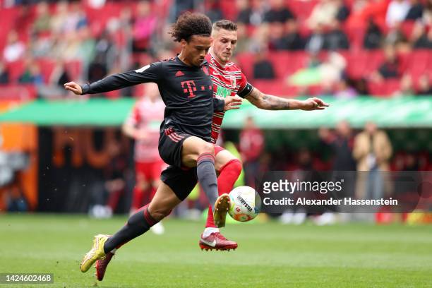 Leroy Sane of Bayern Munich battles for possession with Jeffrey Gouweleeuw of FC Augsburg during the Bundesliga match between FC Augsburg and FC...