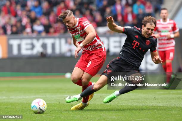 Leon Goretzka of Bayern Munich is challenged by Ermedin Demirovic of FC Augsburg during the Bundesliga match between FC Augsburg and FC Bayern...