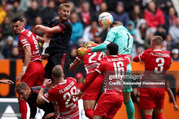 Manuel Neuer of Bayern Munich heads the ball while under pressure from Fredrik Jensen, Ruben Vargas and Mads Pedersen of FC Augsburg during the...