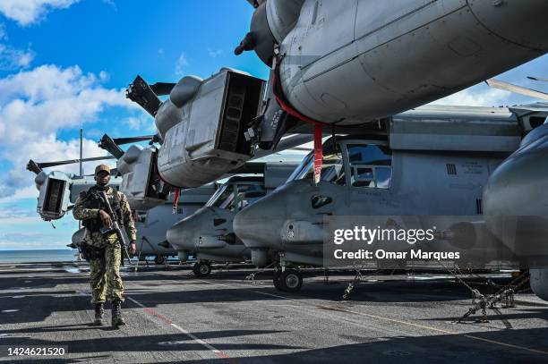 An US Navy officer carries a rifle as he proceeds with a surveillance shift at the flight deck of the USS Kearsarge, a Wasp-class amphibious assault...