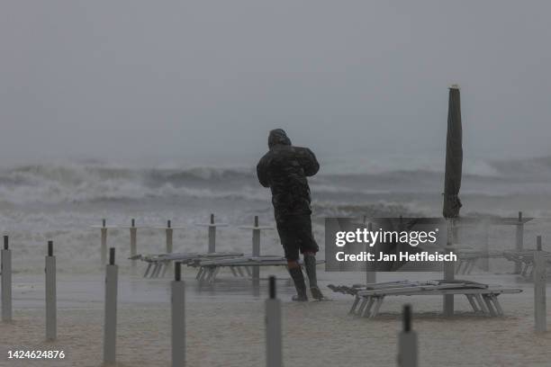 Man shields himself from the wind and rain while walking on flooded beach near Cervia in the Italian region of Emilia Romagna ​on September 17, 2022...