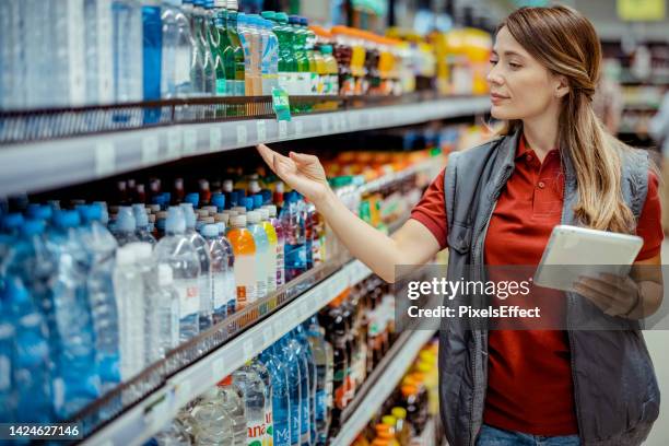 supermarket employe with touchpad going through product aisle - obter inventário imagens e fotografias de stock