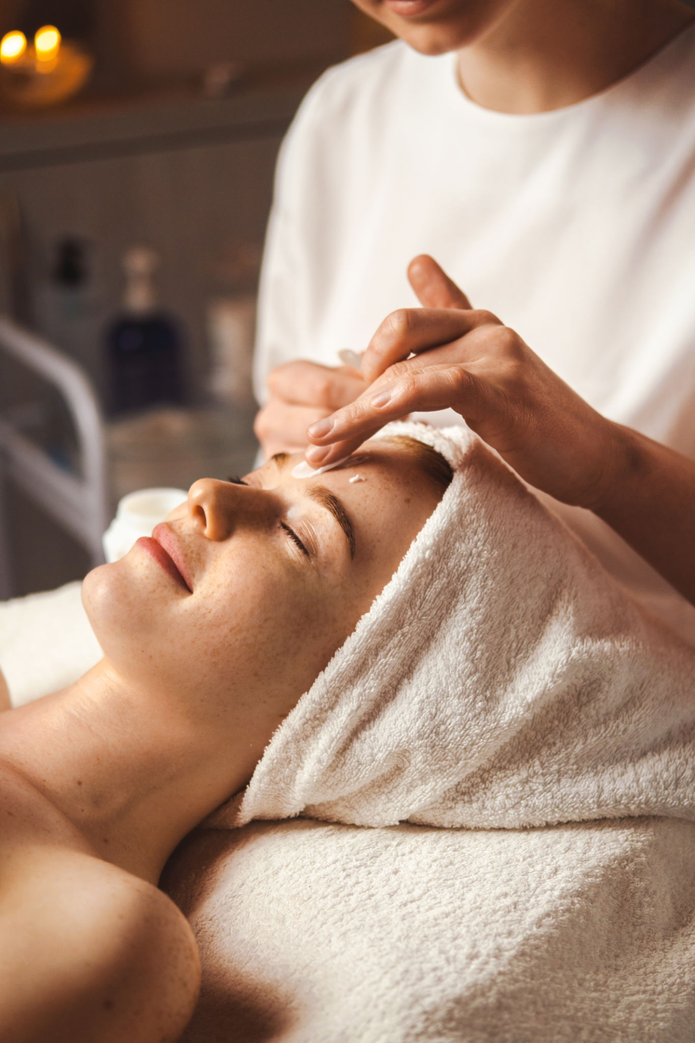 Beautician applying facial cream all over young woman's forehead at spa salon. Skin treatment. Girl facial treatment. Medical health. Beautician applying facial cream all over young woman's forehead at spa salon. Skin treatment. Girl facial treatment. Medical health.