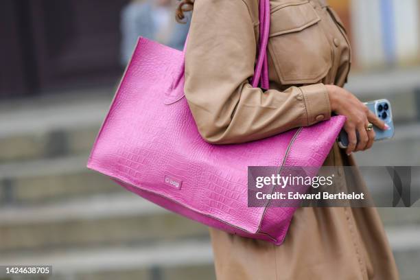 Guest wears a brown shiny leather belted / shirt coat, a pink shiny leather large shoulder bag from O Bag, outside Lovechild 1979, during Copenhagen...