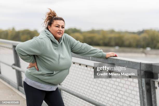obese hispanic woman taking a break while exercising outside - obesity stock pictures, royalty-free photos & images