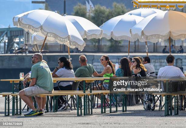 Tourists relax at a bar in Doca da Marinha by the river on September 17, 2022 in Lisbon, Portugal. The number of foreign tourists visiting the...